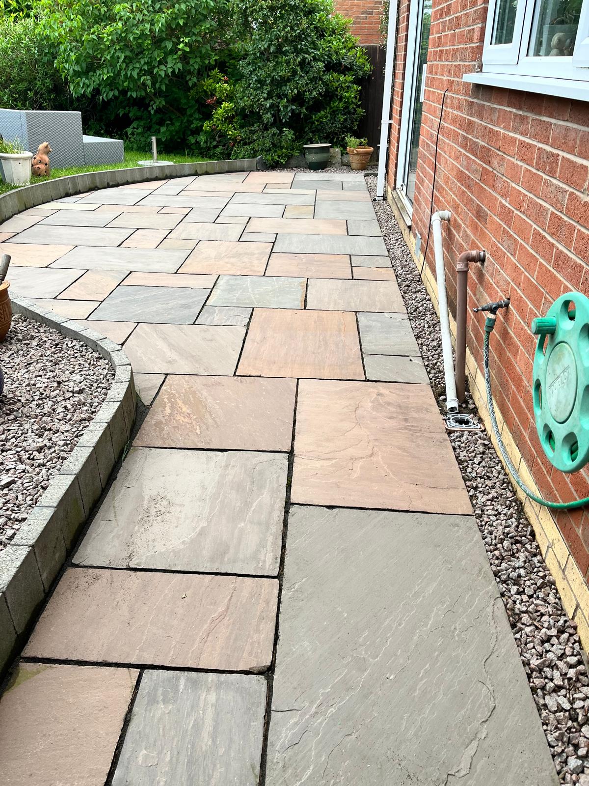 A curved sandstone path edged with gravel beside a brick house