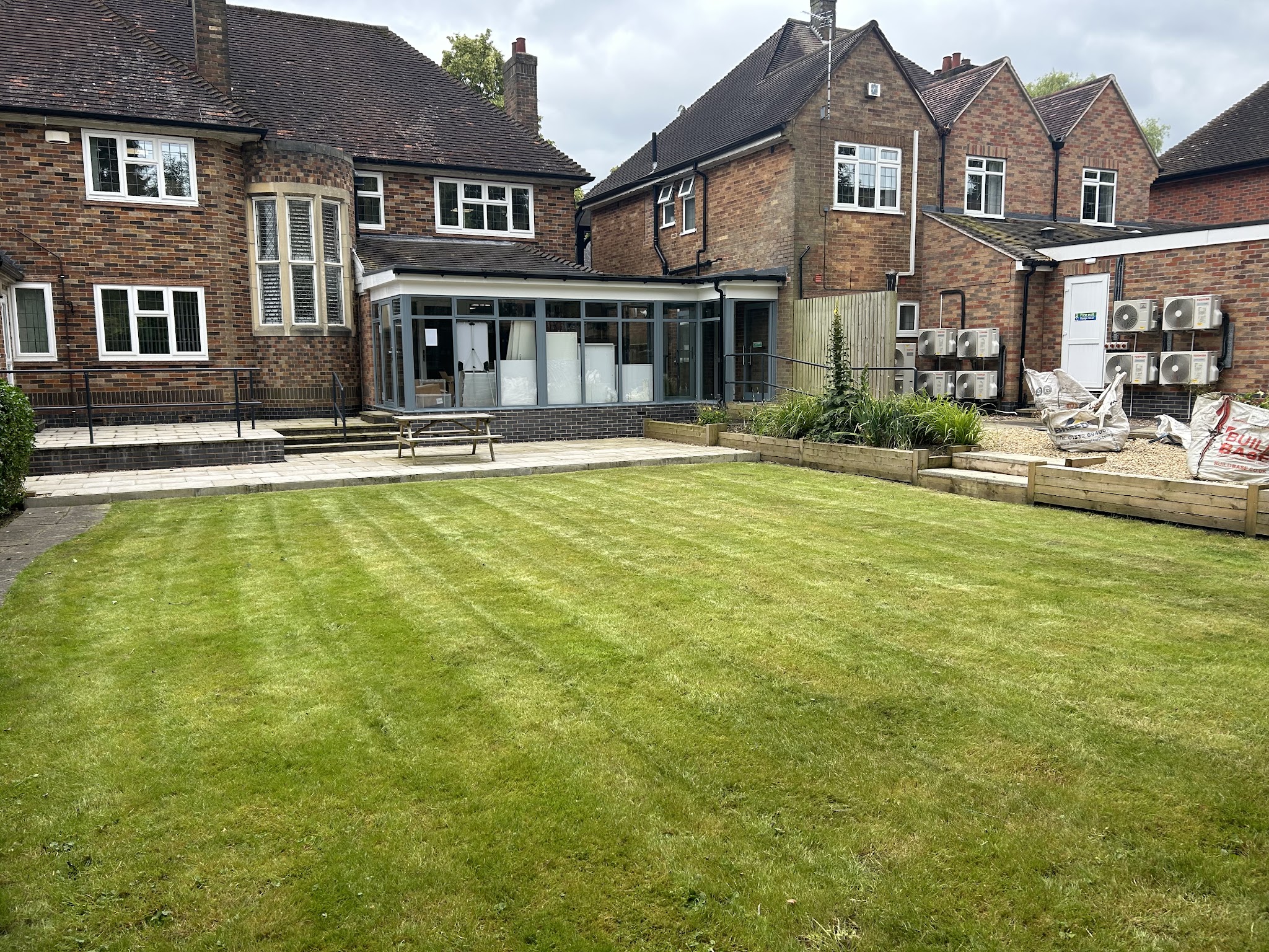 A wide, freshly striped lawn behind a large brick house